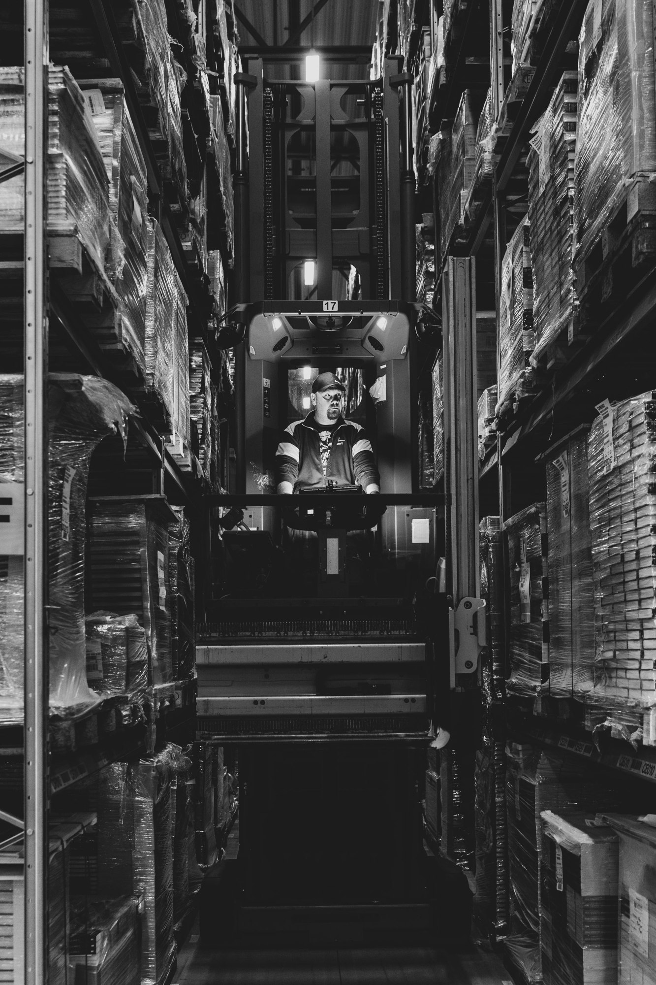 Forklift operator working between warehouse racks in a black and white photograph