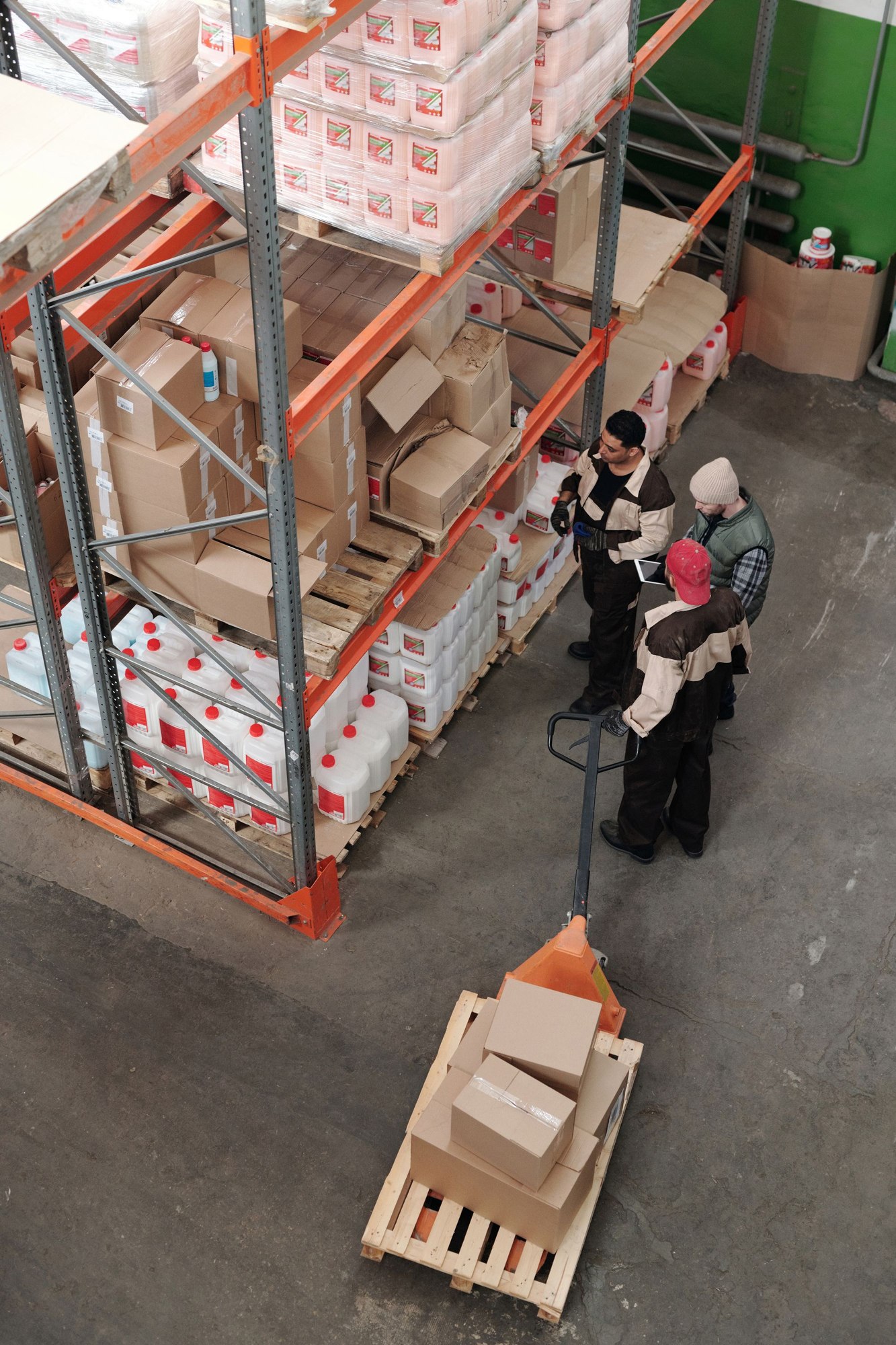 Warehouse employees discussing work beside stocked shelving